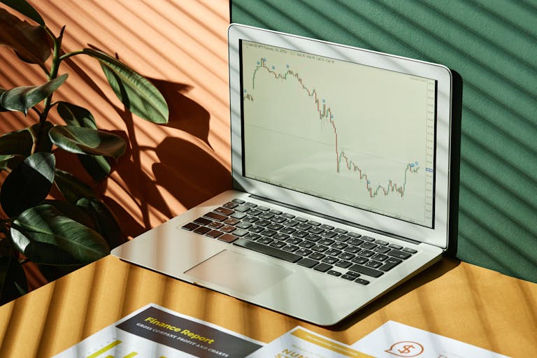 Laptop displaying stock trend lines with warm shadows—representing AI tools for smarter financial decisions in QuickBooks.
